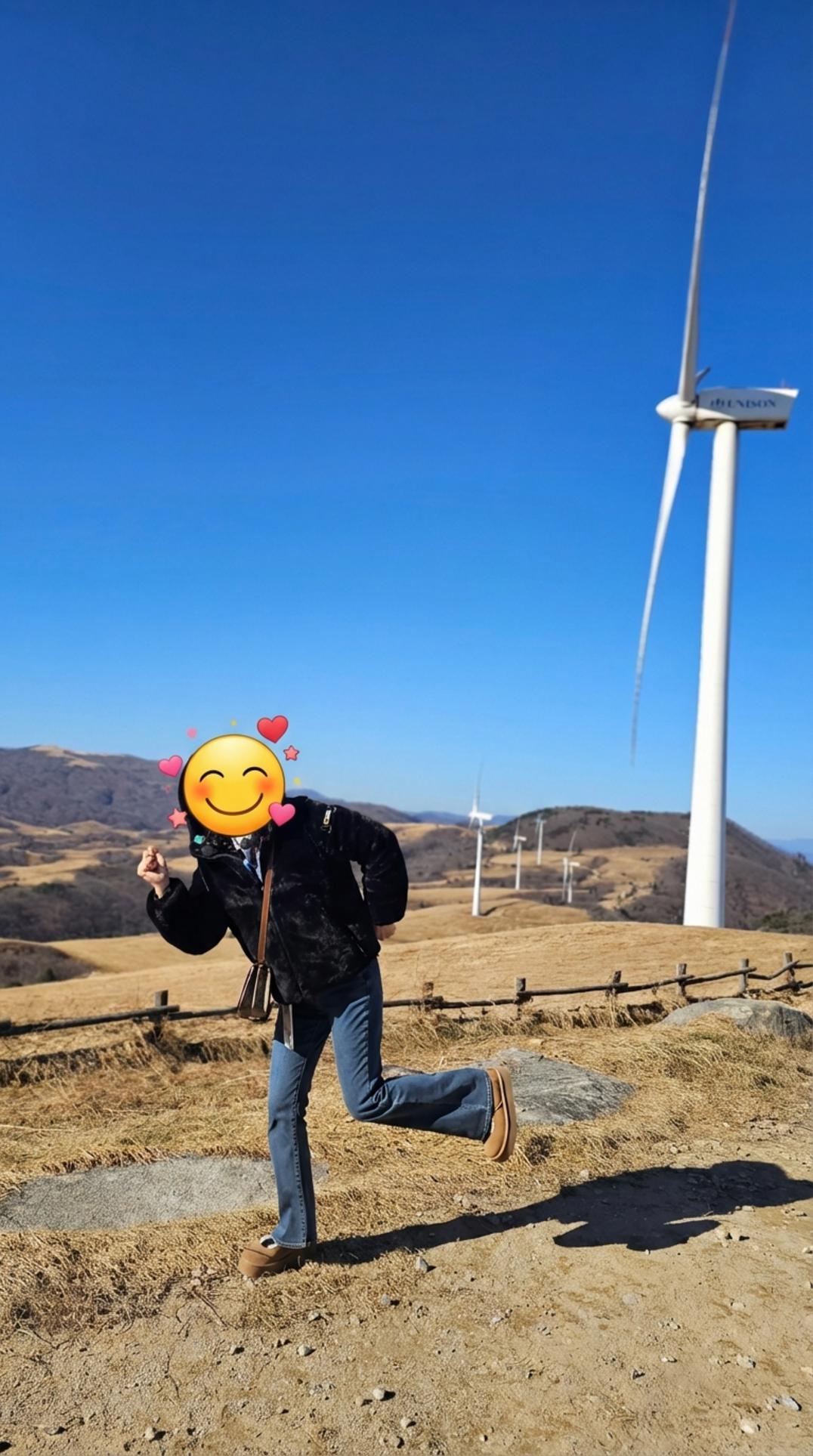 대관령 풍력발전소를 배경으로 활기찬 포즈를 취하고 있는 여성